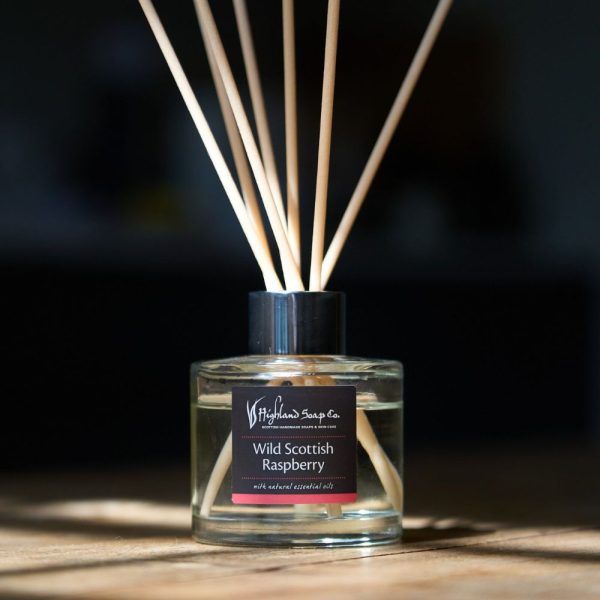 Wild Scottish Raspberry Reed Diffuser van The Highland Soap Company op houten oppervlak in warm zonlicht
