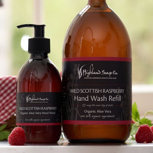 Wild Scottish Raspberry hand wash en grote refillfles van The Highland Soap Company met verse frambozen op de voorgrond