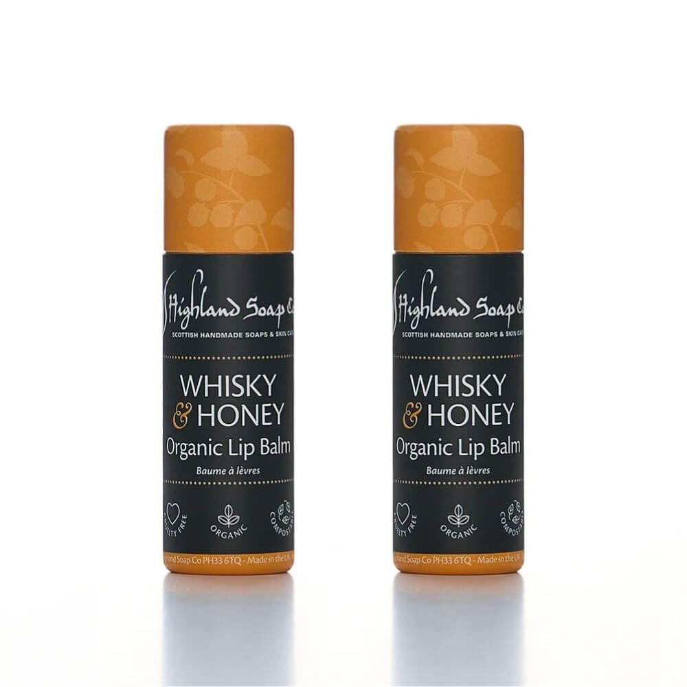 Twee Whisky & Honey lippenbalsems van The Highland Soap Company rechtop naast elkaar op een lichte achtergrond.