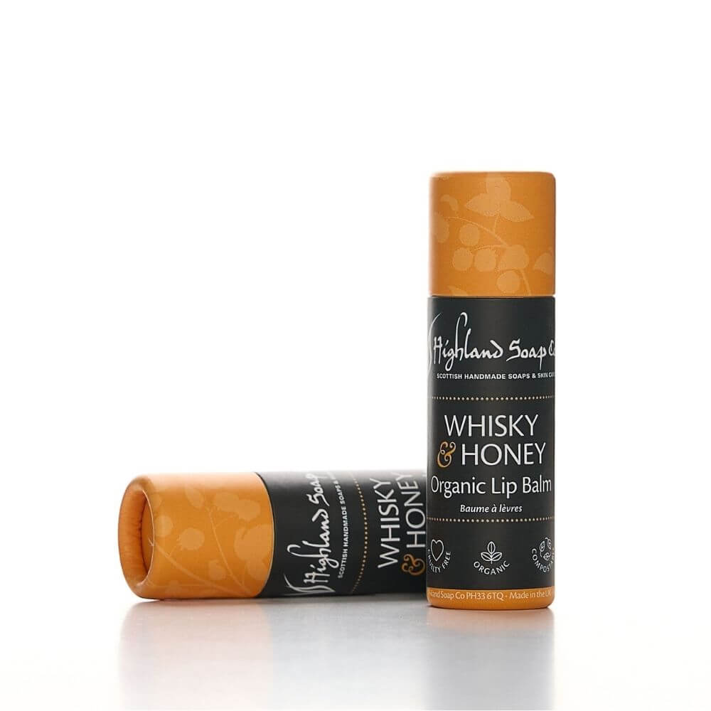 Twee Whisky & Honey lippenbalsems van The Highland Soap Company, één staand en één liggend op een lichte achtergrond.
