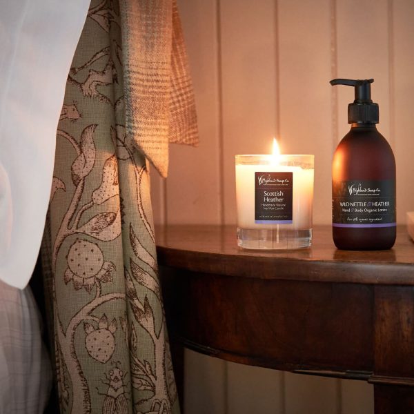 Scottish Heather – Geurkaars & Bodylotion – brandende kaars en lotionfles op houten tafel