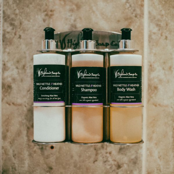 Wild Nettle & Heather – Badkamerverzorging – wandhouder met conditioner, shampoo en bodywash tegen natuurstenen tegelwand
