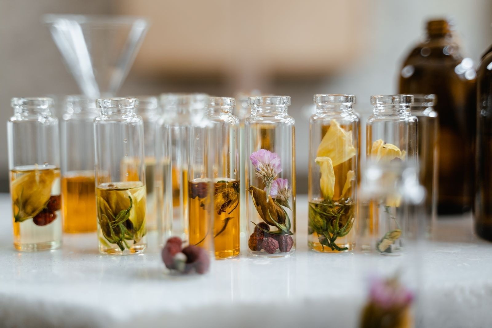 Glazen flesjes met plantenoliën en verse kruiden naast elkaar op een tafel