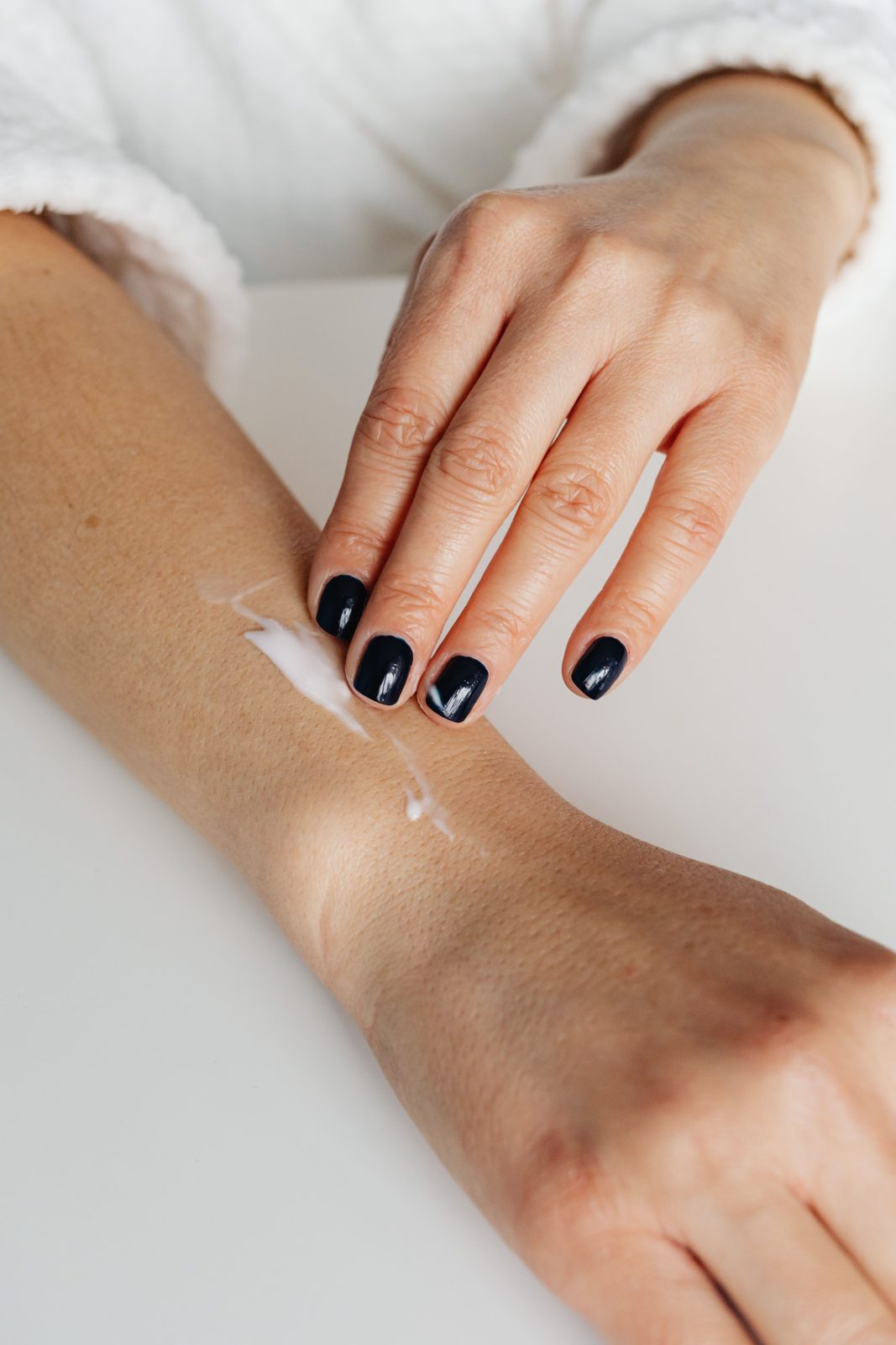 Een hand die lotion uitsmeert op de binnenkant van een arm