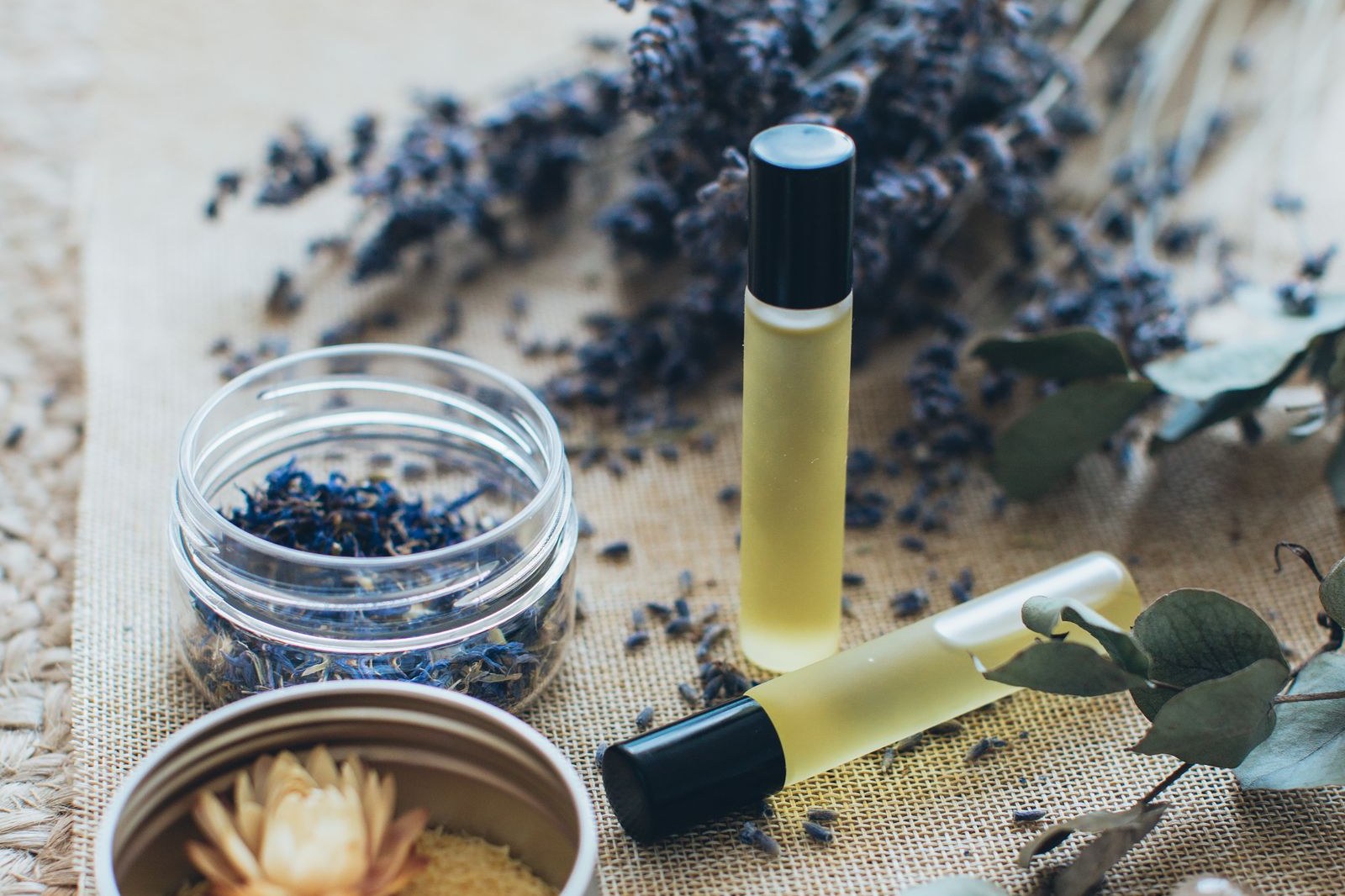 Flesjes met essentiële olie tussen gedroogde lavendel en eucalyptus